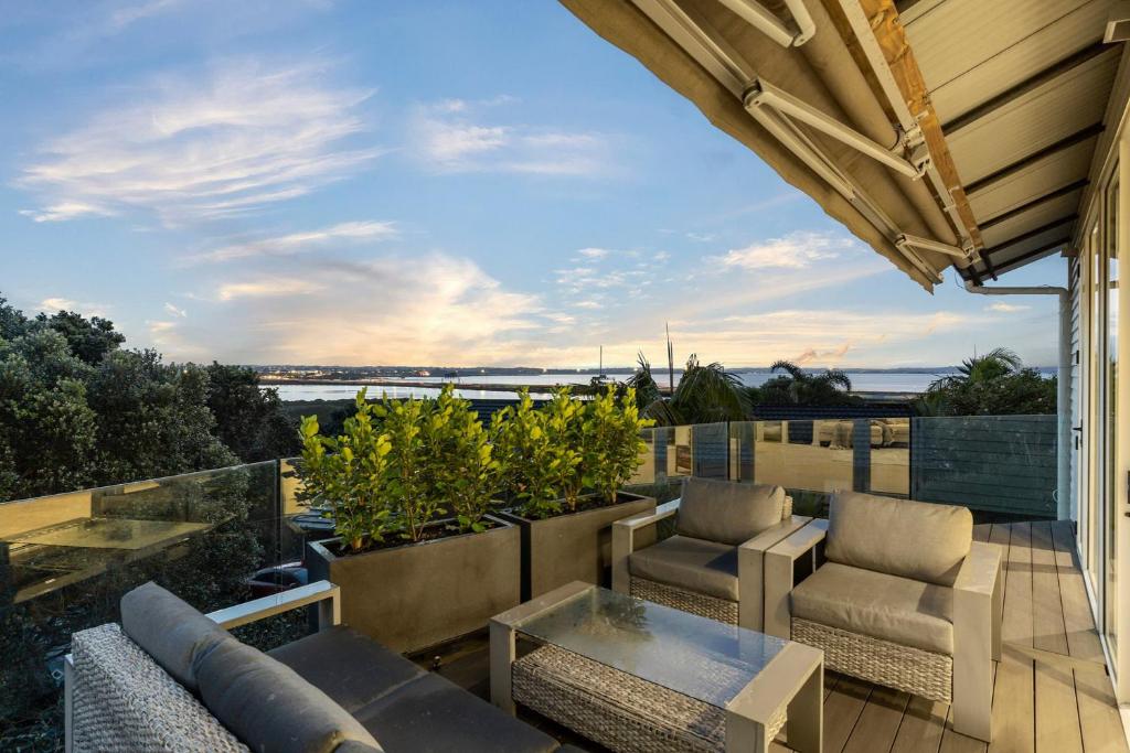 a patio with chairs and a table on a balcony at Ocean view Designer Standalone Villa Big Deck in Auckland