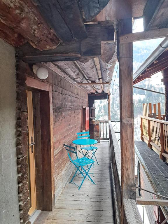 a wooden deck with a blue table on it at Le cocon de Mâche in Hérémence