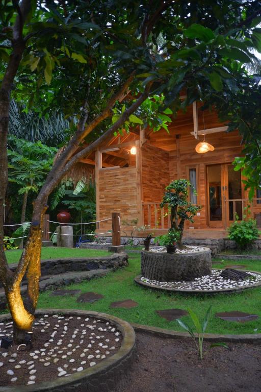 a log cabin with a tree in front of it at Beda gaya ecolodge Rangsot 2 in Tanjung