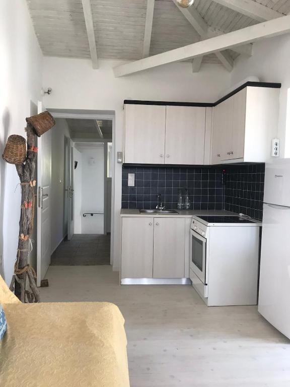 eine Küche mit weißen Schränken und einer schwarzen Fliesenwand in der Unterkunft Kasimiotis studio in Koroni