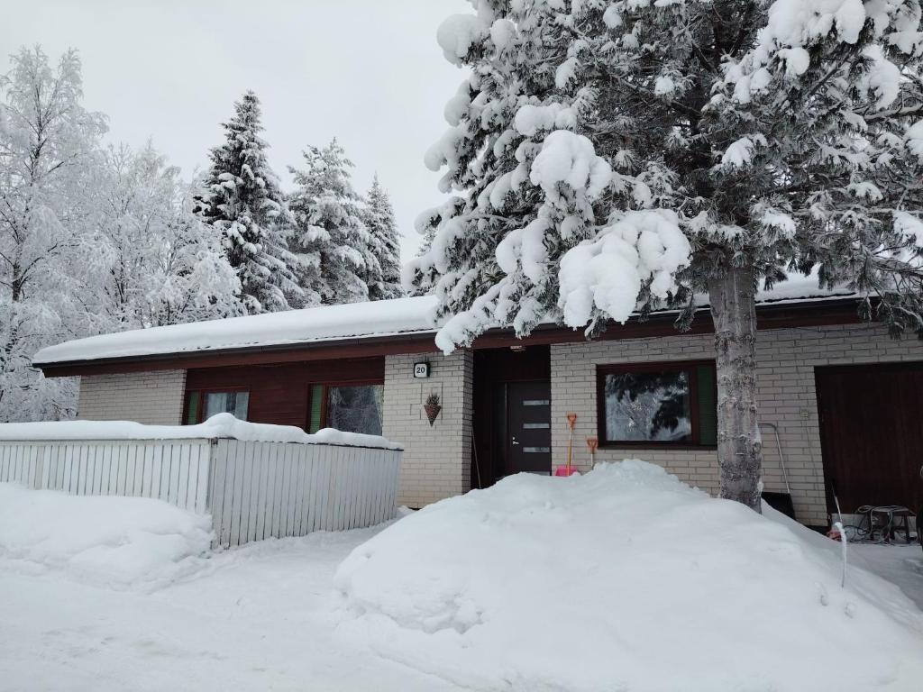 a snow covered house with a tree in front of it at NorthSlope in Rovaniemi
