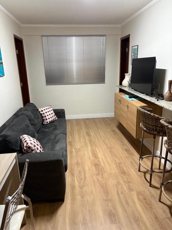 a living room with a black couch and a desk at Ipê Rosa Apartamento in Brasília