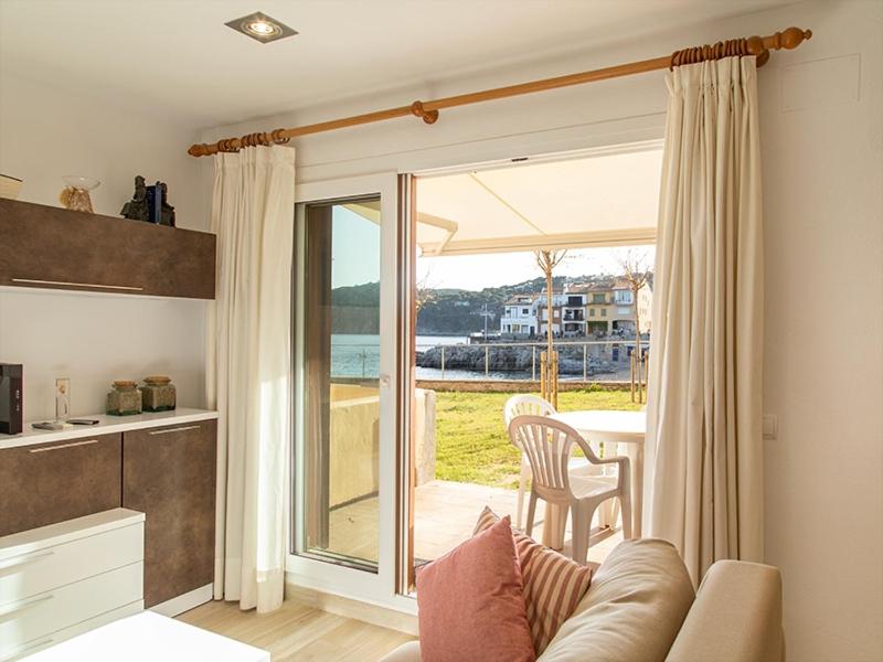 a living room with a couch and a kitchen with a balcony at Playa Canadell MAR P primera línea de mar con terraza - WeHost Costa Brava in Calella de Palafrugell