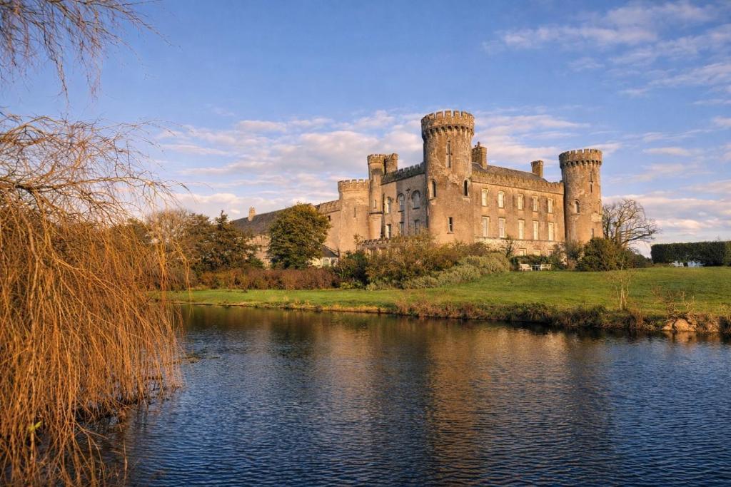 a castle on a hill next to a body of water at Barmeath Castle Guest House in Dún Léire