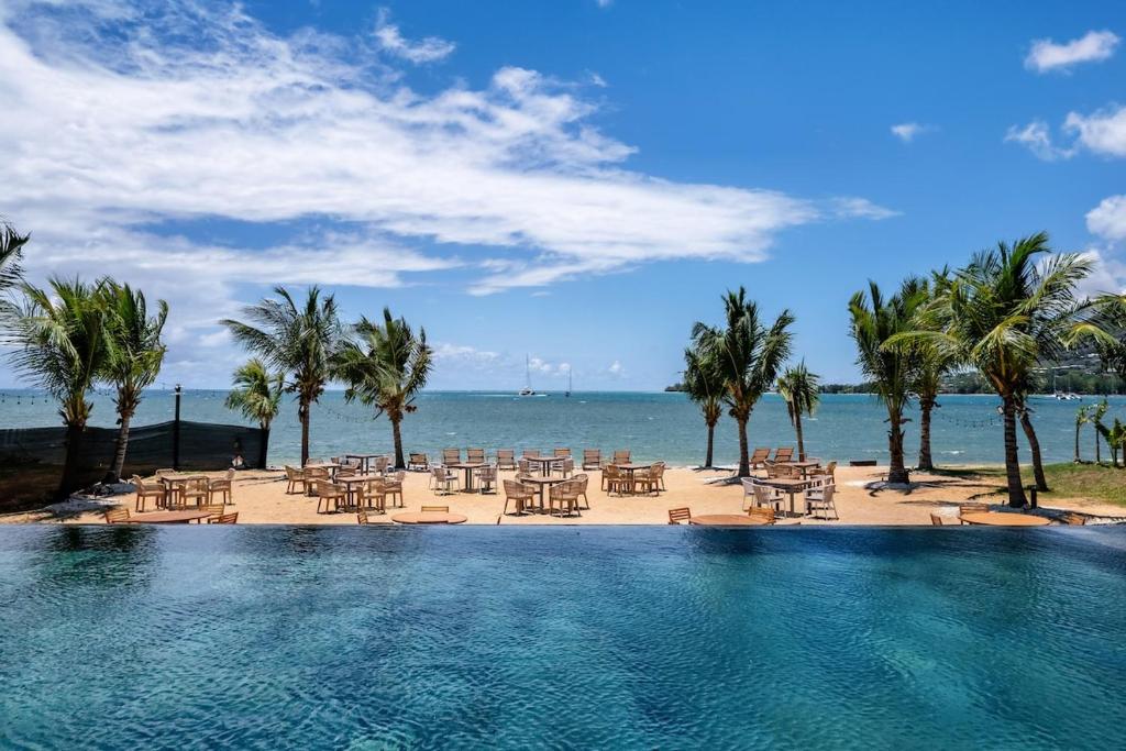 a swimming pool with tables and chairs and the ocean at Asmara Alora E3 - Beachfront in Rivière Noire