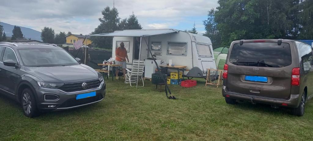two vehicles parked in a field with a camper and a tent at Camping Dorfer in Spielberg