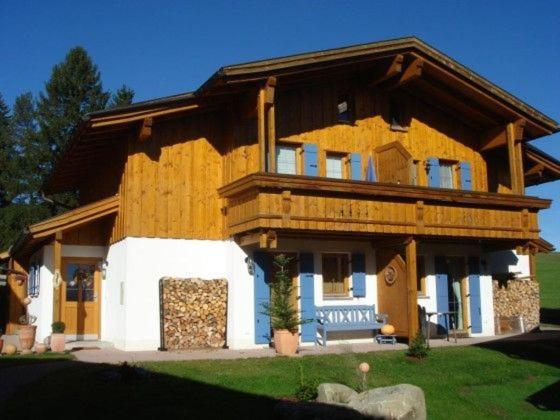 a large wooden house with a porch on a lawn at Meisters Ferienhaus in Lechbruck