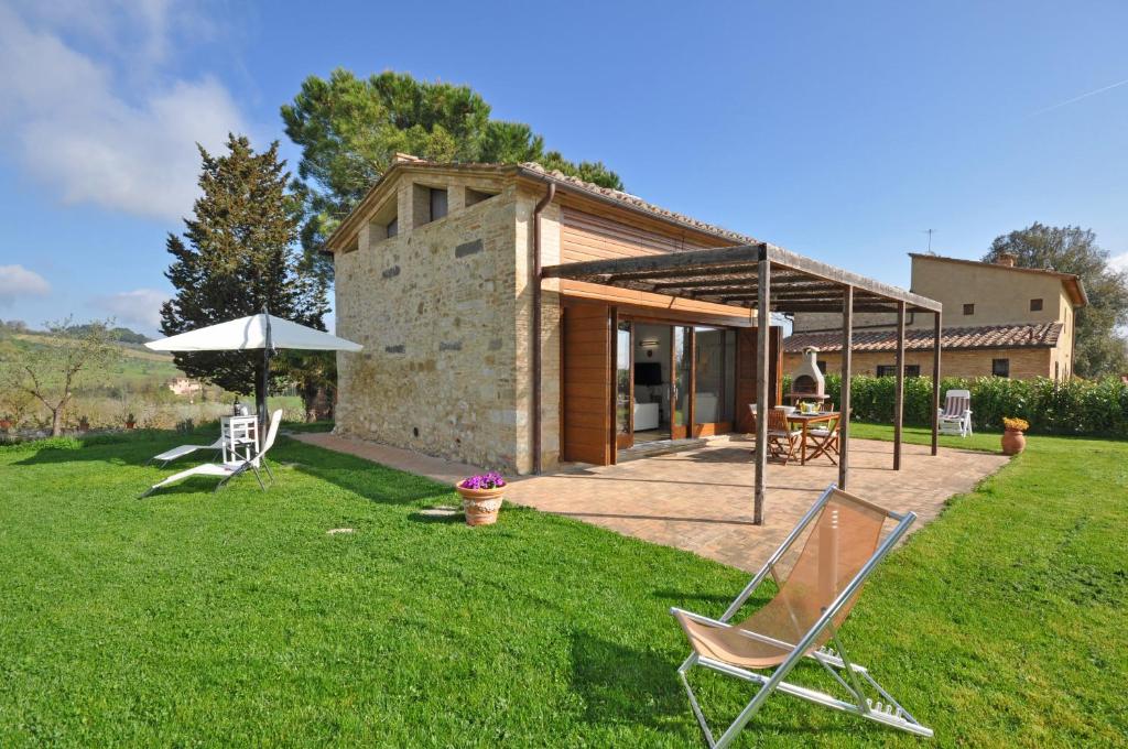 una casa con un cortile con sedie e ombrellone di Capannino by PosarelliVillas a Ponte A Bozzone