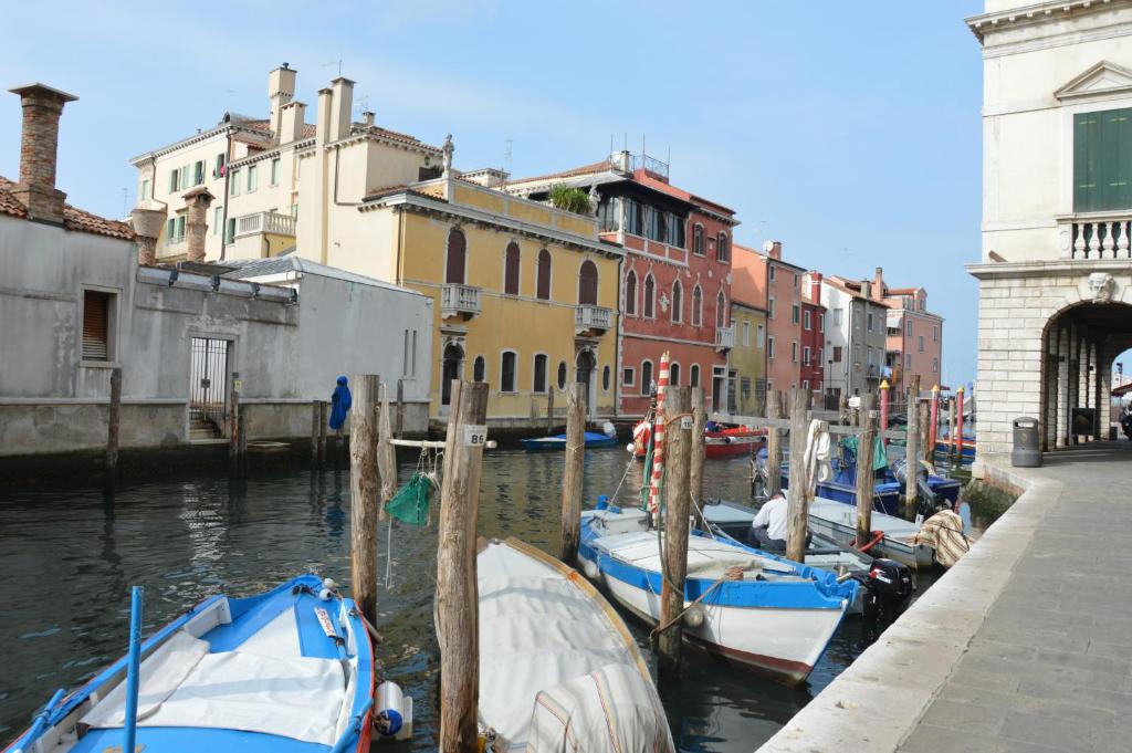 a group of boats docked in a canal with buildings at Hotel del Mar in Sottomarina