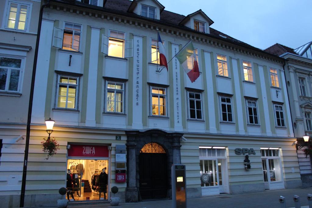 ein großes weißes Gebäude mit zwei Flaggen darauf in der Unterkunft VIKSI hostel in Ljubljana