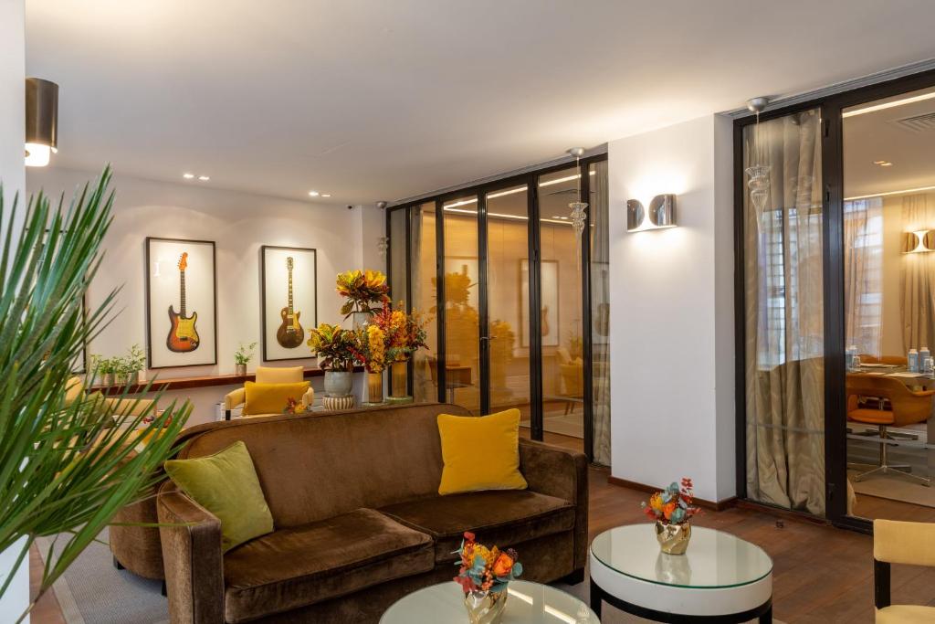 ein Wohnzimmer mit Sofa und Tischen in der Unterkunft Hôtel Le Colisée in Paris
