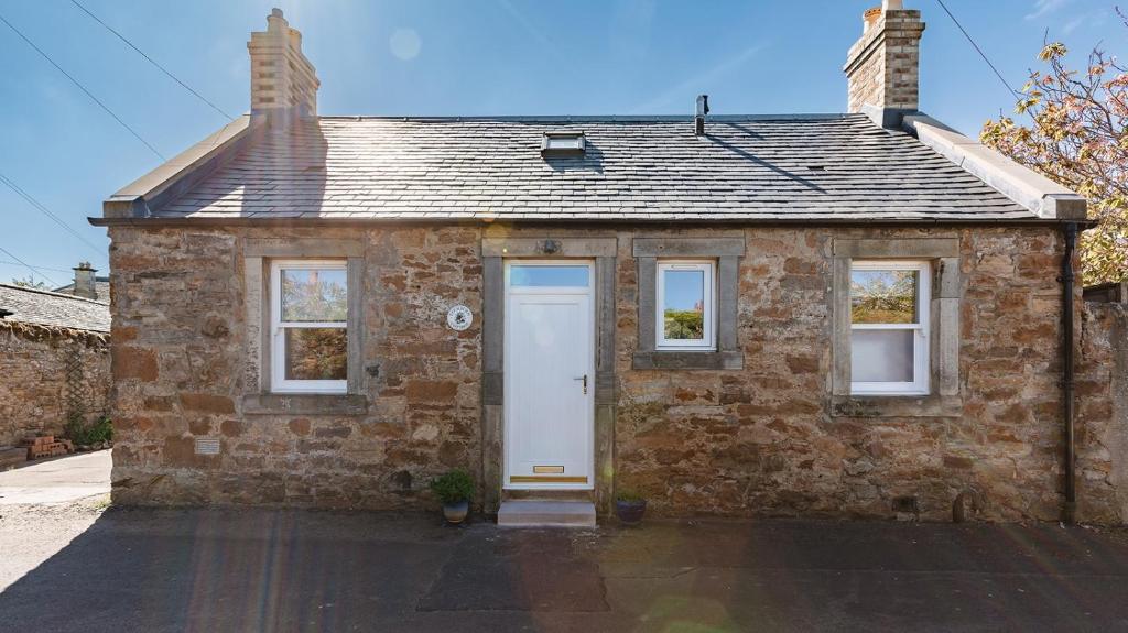 a brick house with a white door and windows at Lochburn Cottage in Elie