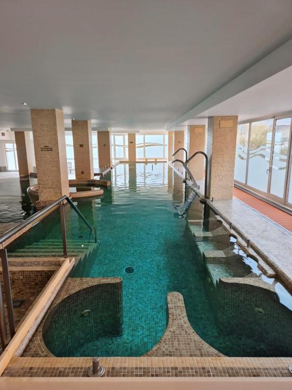 a swimming pool with green water in a building at Hotel Bienestar Moaña in Moaña