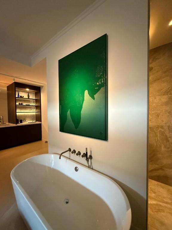 eine Badewanne in einem Badezimmer mit einem grünen Gemälde an der Wand in der Unterkunft TEAM bnb in De Koog