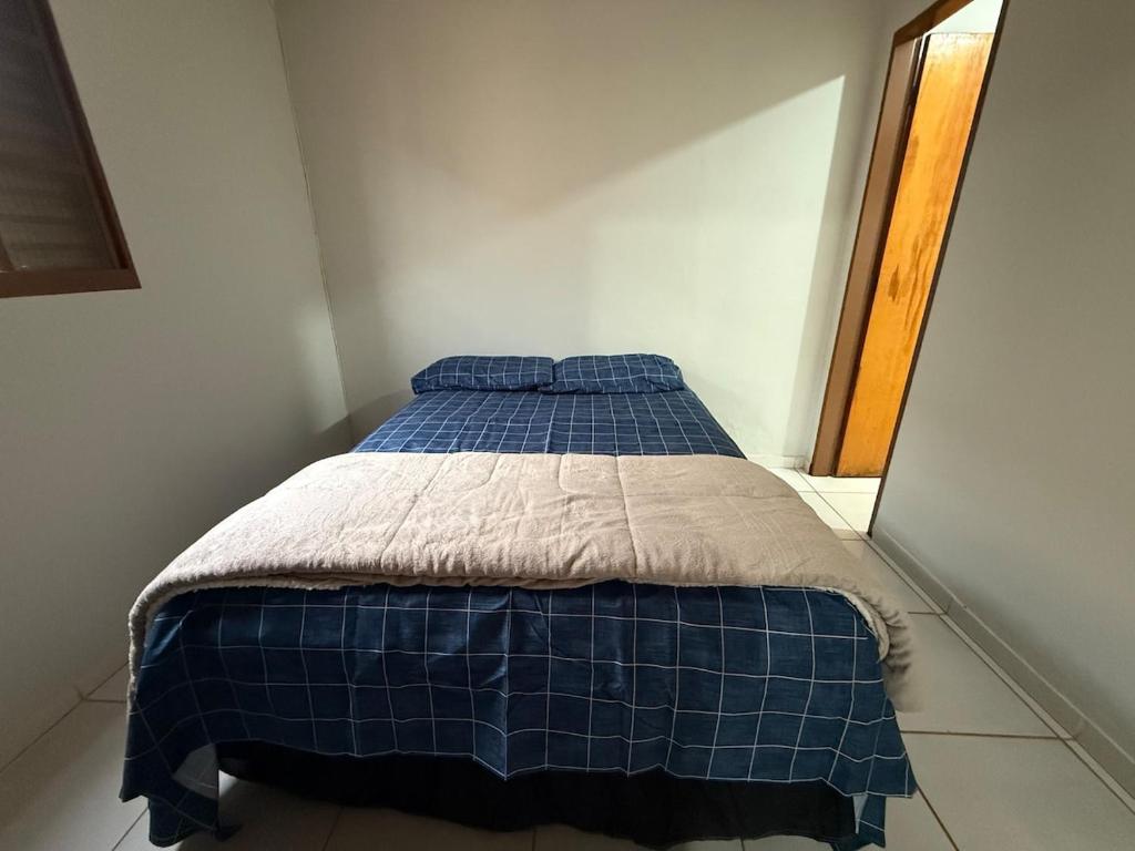 a bed in a room with a blue blanket on it at Kitnet Econômica e Funcional in Campo Grande
