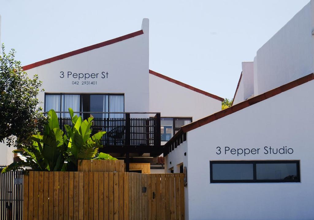 a white building with a fence in front of it at 3 Pepper Street by African Perfection in Jeffreys Bay