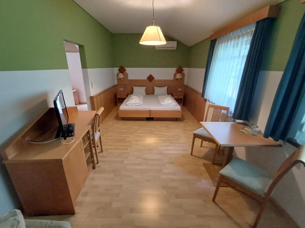 ein Zimmer mit einem Bett und einem Schreibtisch mit Fernseher in der Unterkunft Georgshof in Podersdorf am See
