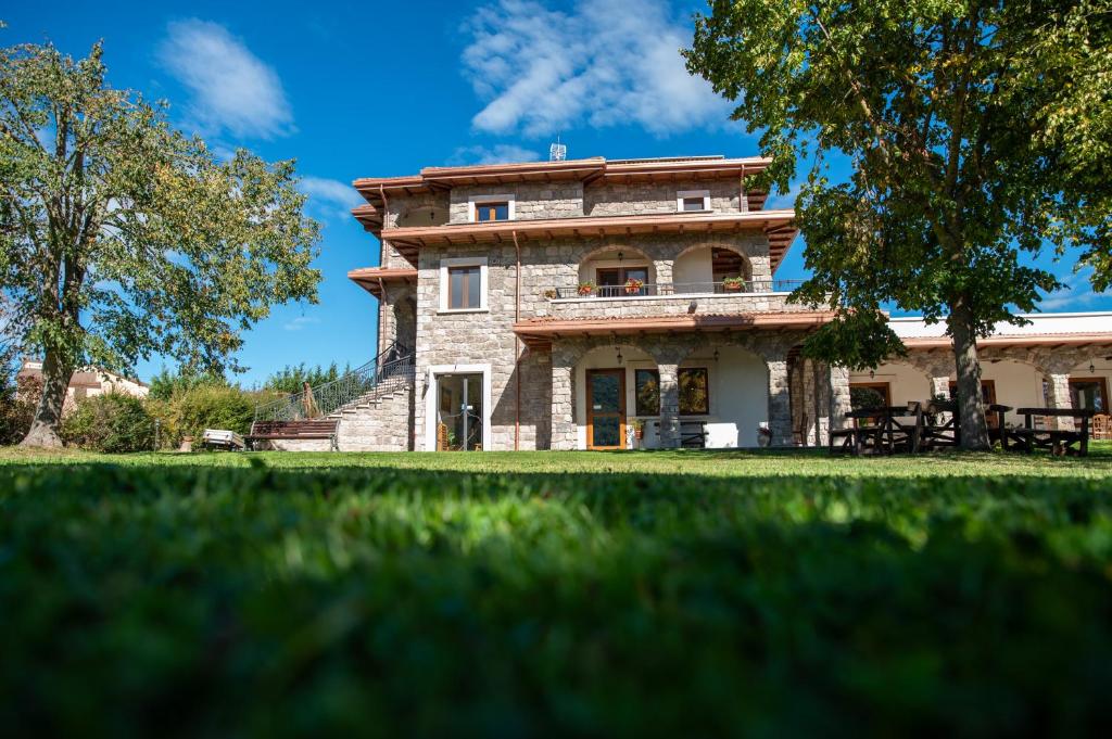 a large stone house with a grass yard at Agriturismo Cupello in Cagnano Amiterno