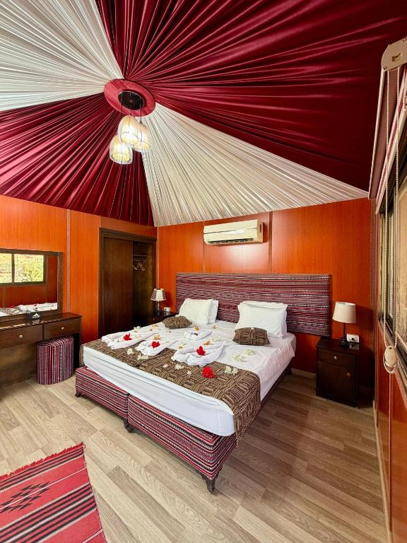 a bedroom with a large bed with a red ceiling at Rum Oasis Luxury Camp in Wadi Rum