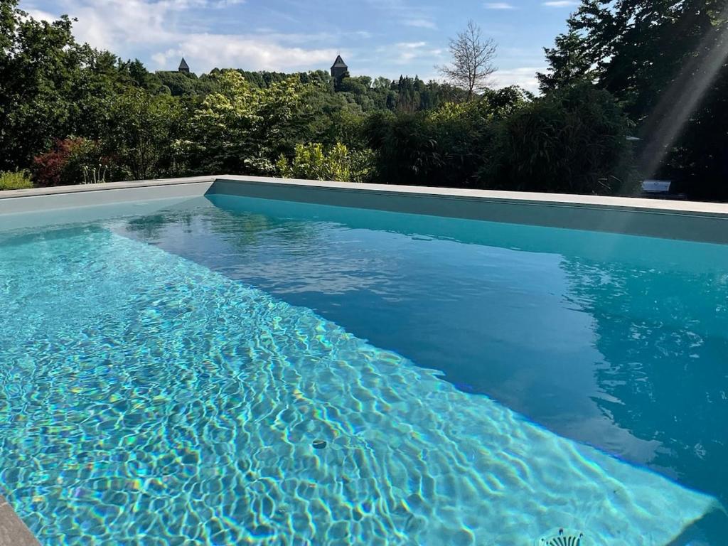 a large swimming pool with blue water at Schiller Ferienwohnung, Pool, Nideggen, Eifel in Nideggen