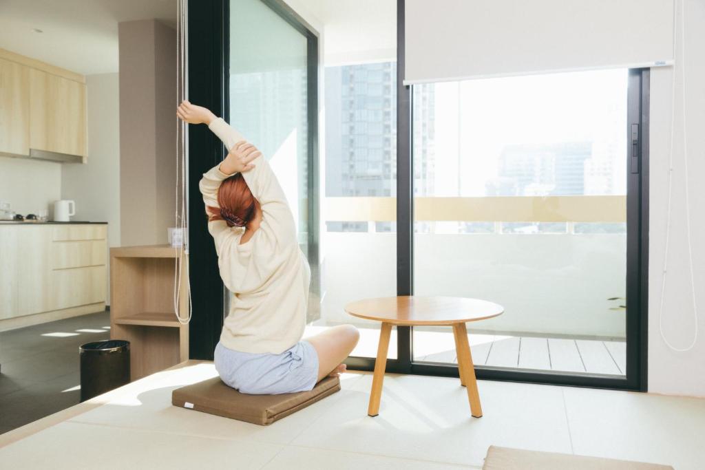 a woman doing a yoga pose in a living room at LiveZen Bangkok Sukhumvit in Klong Toi