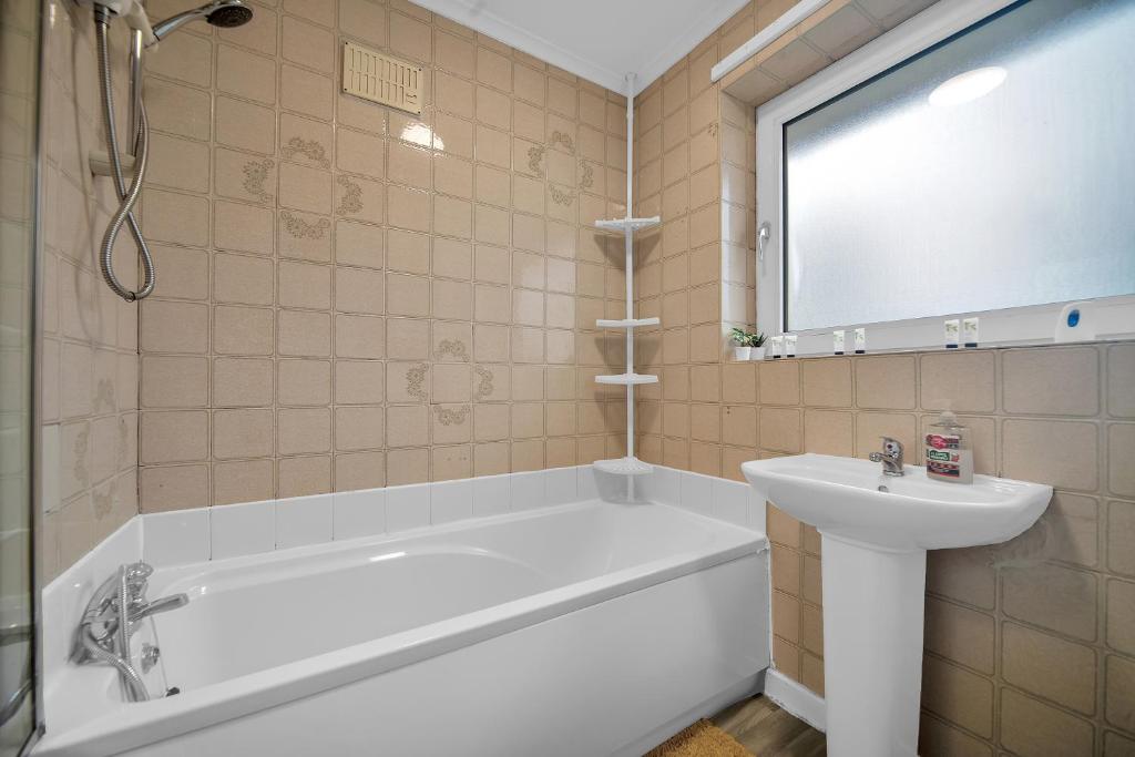 a bathroom with a tub and a sink at Spacious 4-Bed House, & Prime Location Solihull in Olton