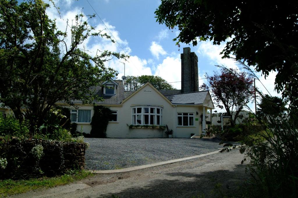 a white house with a chimney on a driveway at Rosedene Guest House in Pembroke