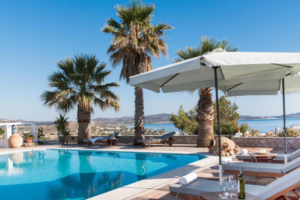 a swimming pool with an umbrella and palm trees at Villa Mina in Adamantas