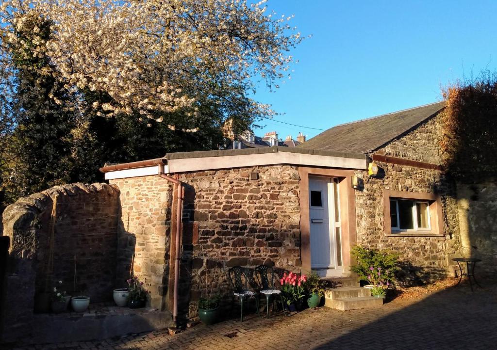 a brick house with a white door and chairs at The Wedale Bothy in Stow