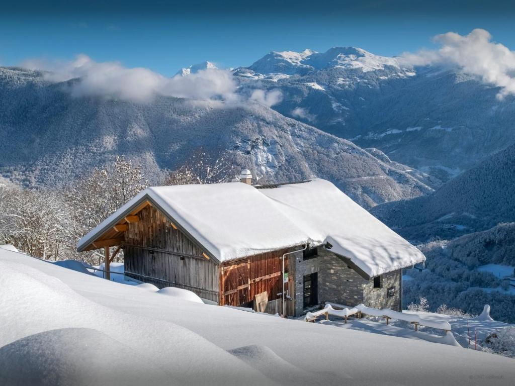 a cabin covered in snow with mountains in the background at Chalet Confidentiel - OVO Network in Doucy