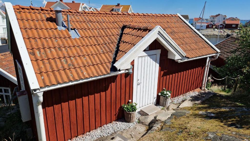 a red house with a red roof with two plants at Lilla huset in Klädesholmen