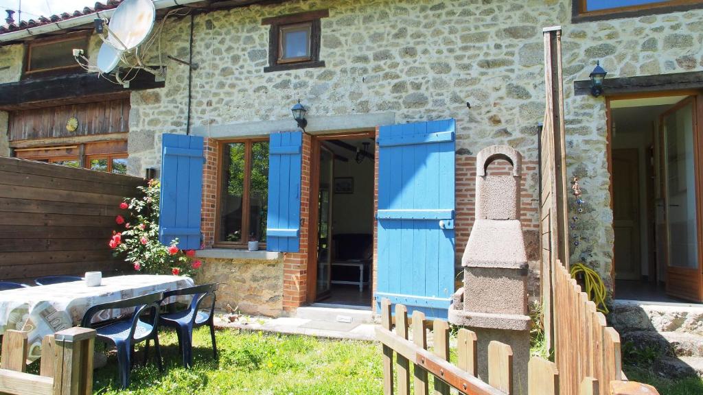 a house with blue doors and a table in the yard at Les 3 pruniers in Cieux
