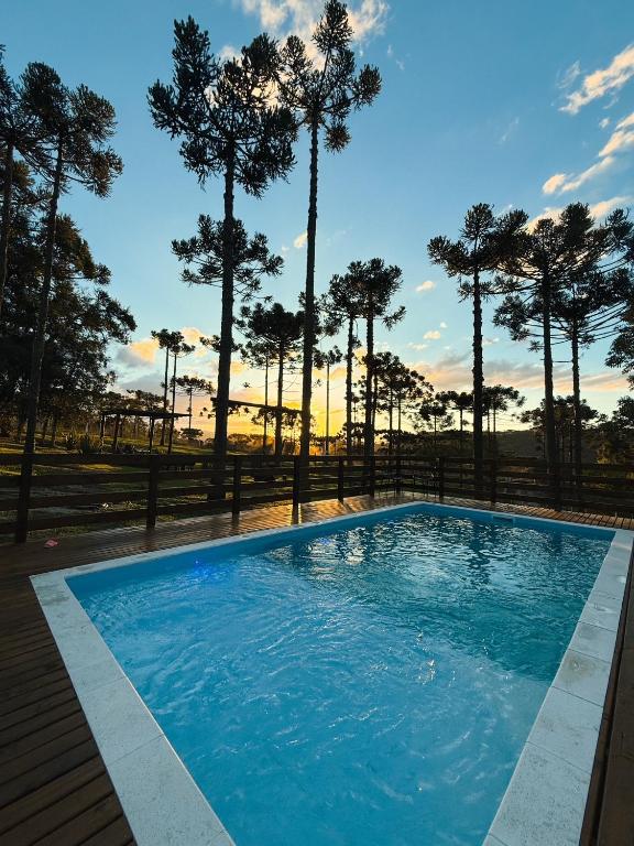 a blue swimming pool with trees in the background at Namastê - Hospedaria de Altitude in Urubici