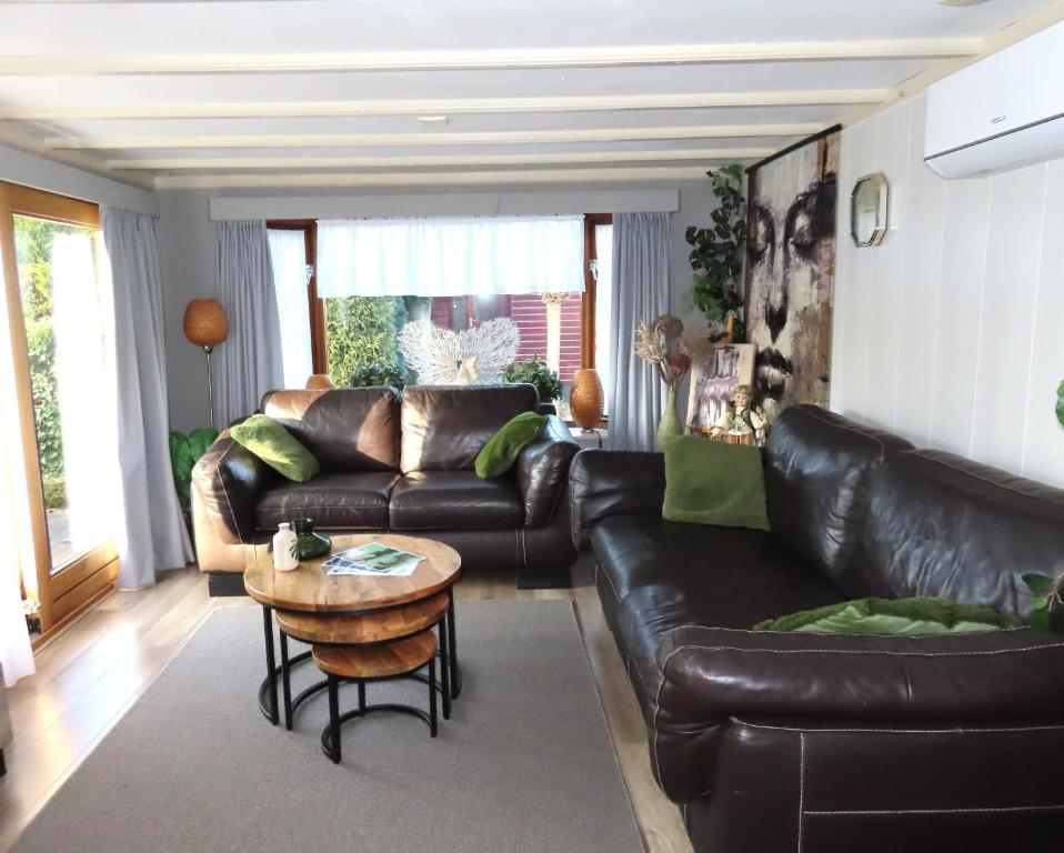a living room with a leather couch and a table at Veluwe Park Reewold Chalet Eclipse in Putten