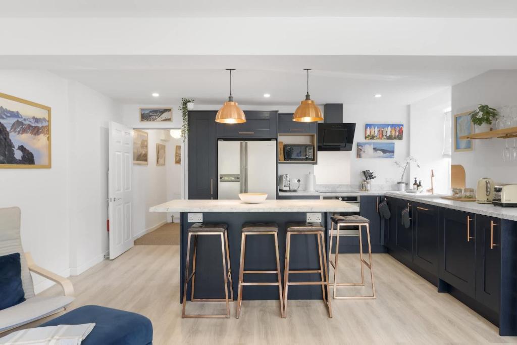 a kitchen with blue cabinets and a island with bar stools at Beautiful Apartment with Parking Central Exeter in Dean