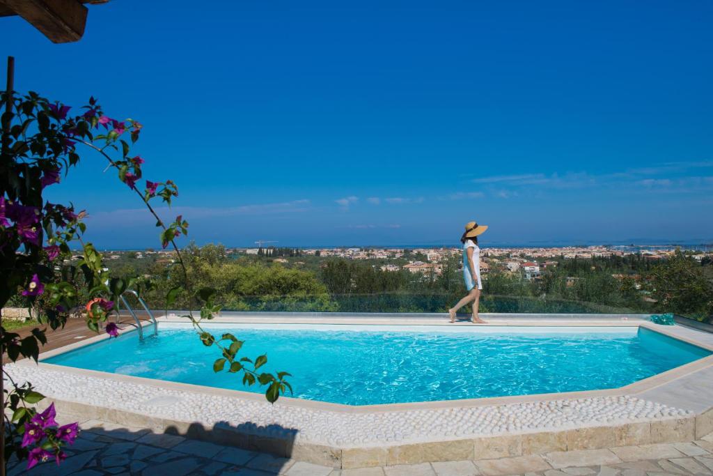 una persona parada en el borde de una piscina en Alea Resort Villas, en Lefkada