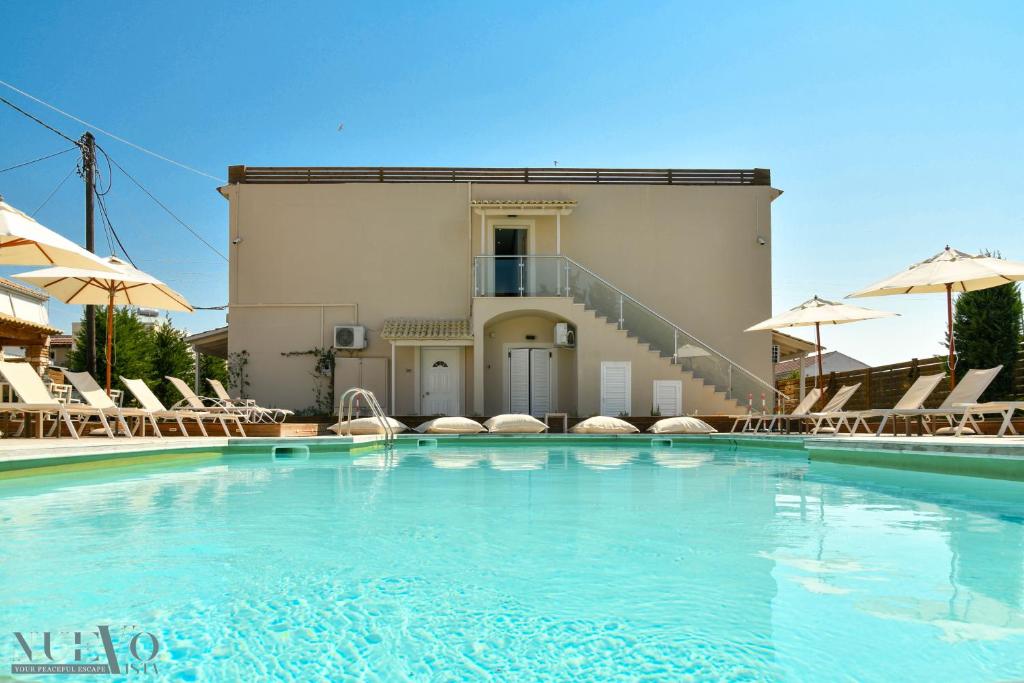a swimming pool with chairs and a building at Nuevo Vista in Kavos