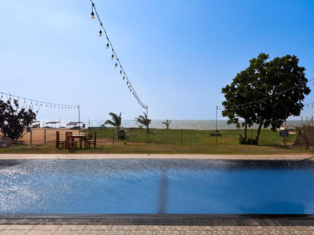 a swimming pool with a picnic table and the ocean at Atarah Beach Hotel in Negombo
