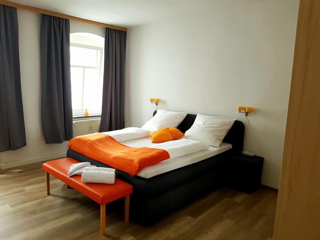 ein Schlafzimmer mit einem großen Bett mit einer orangefarbenen Decke in der Unterkunft Ferienwohnung 1 Christiansdorf Freiberg in Freiberg