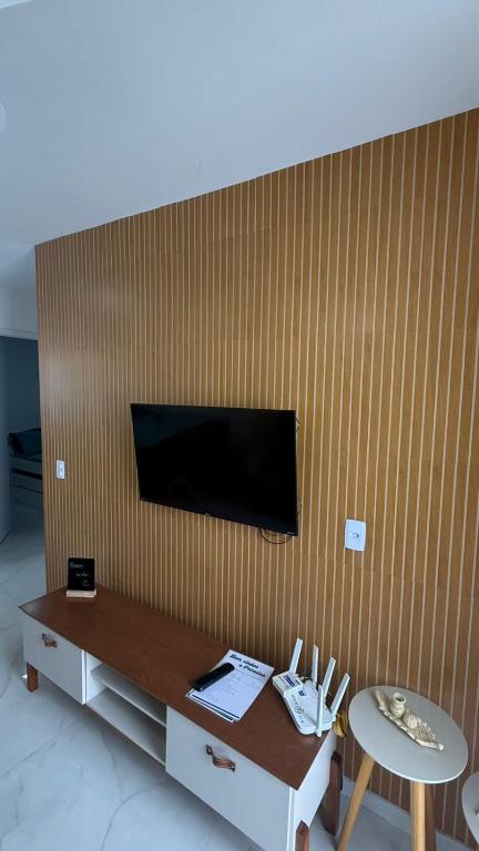 a living room with a table and a tv on a wall at Casa nova e aconchegante em condomínio in Petrolina