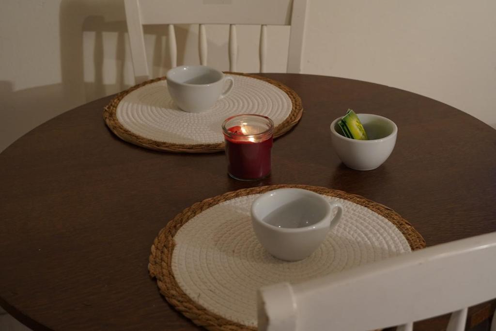 two plates and bowls on a table with a candle at Studio - Free Parking - Netflix - Wi-Fi in Brive-la-Gaillarde