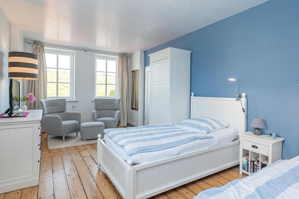 ein Schlafzimmer mit einem weißen Bett und einer blauen Wand in der Unterkunft Elbkajüte in Grünendeich