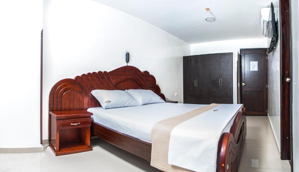 ブカラマンガにあるHotel Isla Mayorのベッドルーム1室(大型ベッド1台、木製ヘッドボード付)
