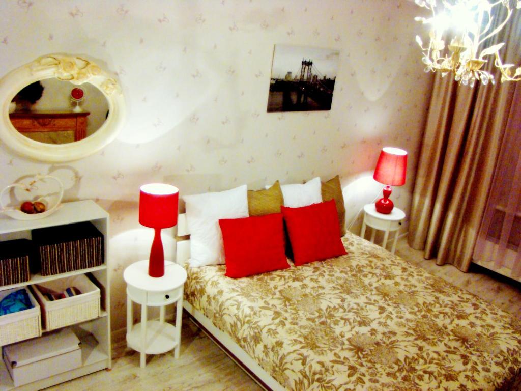 a bedroom with a bed with red pillows and a mirror at Elegant Apartment in Rīga
