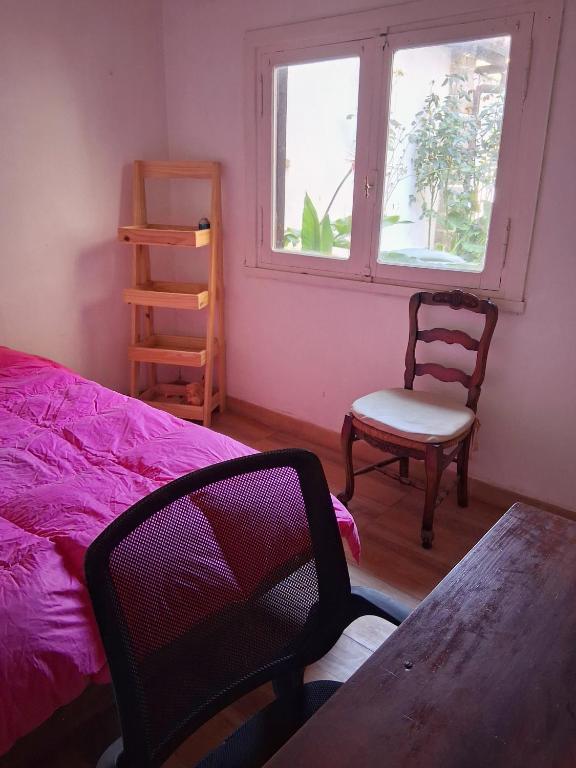 a bedroom with a bed and a chair and a window at Castelli b&b in Mar del Plata