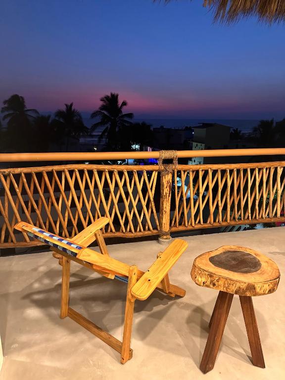 a wooden chair and a stool on a balcony at Hotel Almendros Bonfil in Acapulco