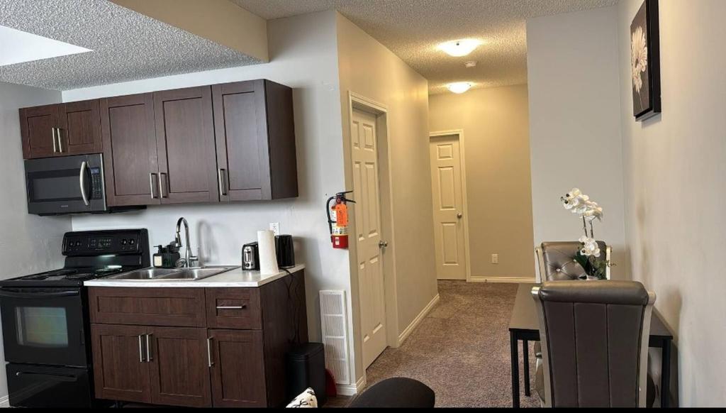 a kitchen with wooden cabinets and a sink and a stove at Quiet Comfortable 1-Bedroom in Calgary
