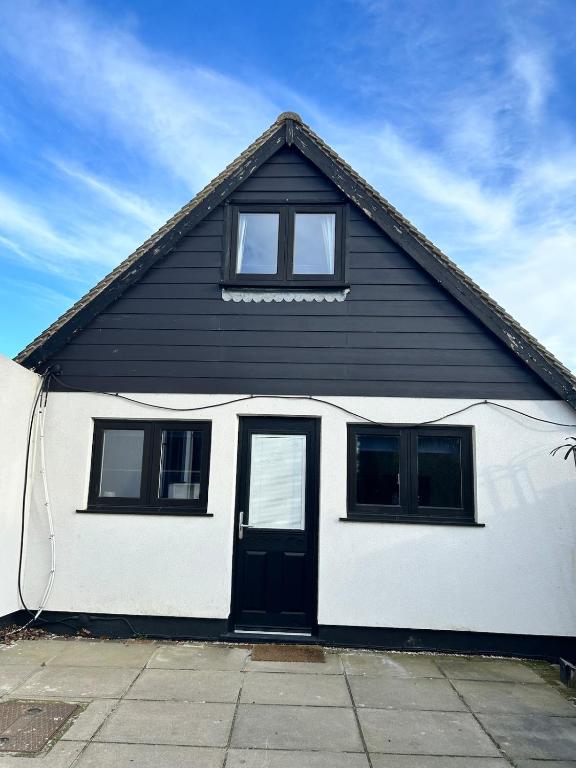 a black and white house with a black door at The old greengrocers Battlesbridge in Rawreth