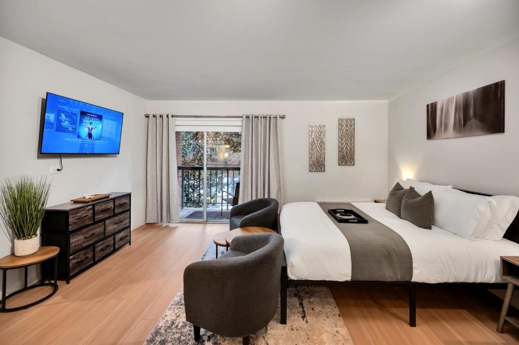 a bedroom with a large bed and a tv at Upscale Midtown Studio and Private Balcony in Raleigh