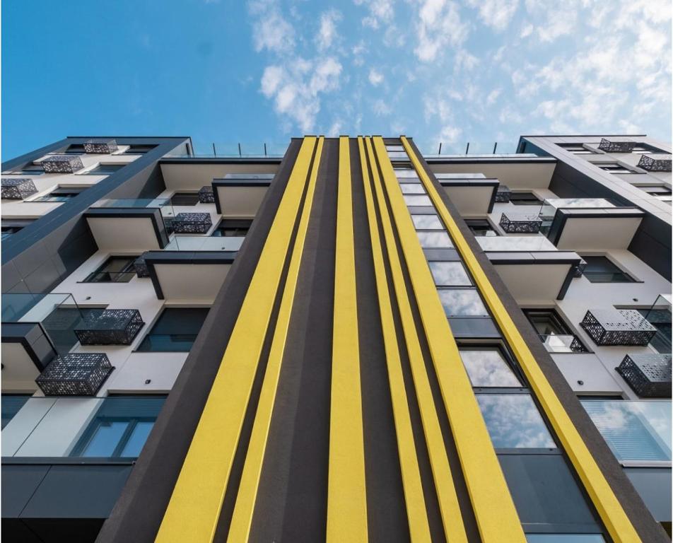 a tall yellow and gray building with windows at SOL LUX Tuzla in Tuzla